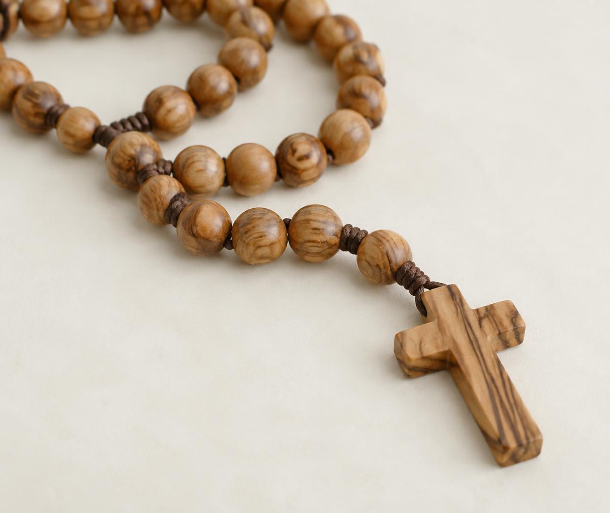 Olive wood rosary beads laid out on a cream surface